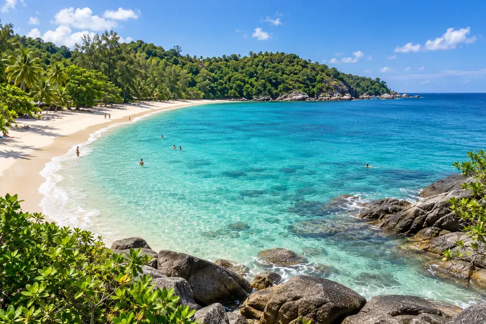 Surin Beach clear blue bay, pale sand, granite rocks, and lush headlands
